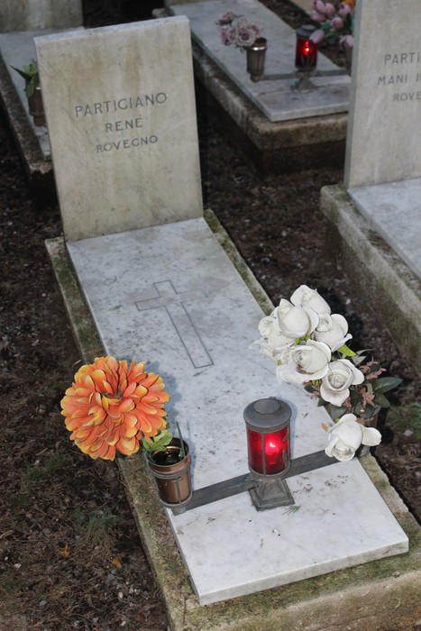 Tombe di partigiani decorate con fiori e candele, in onore dei caduti per la libertà.