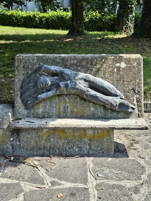 Monumento alla Resistenza, scultura in bronzo che rappresenta un corpo disteso su una panchina in un parco.