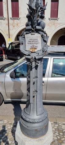 Targa commemorativa a Vidori, decorata con elementi distintivi e colocata in un contesto urbano.