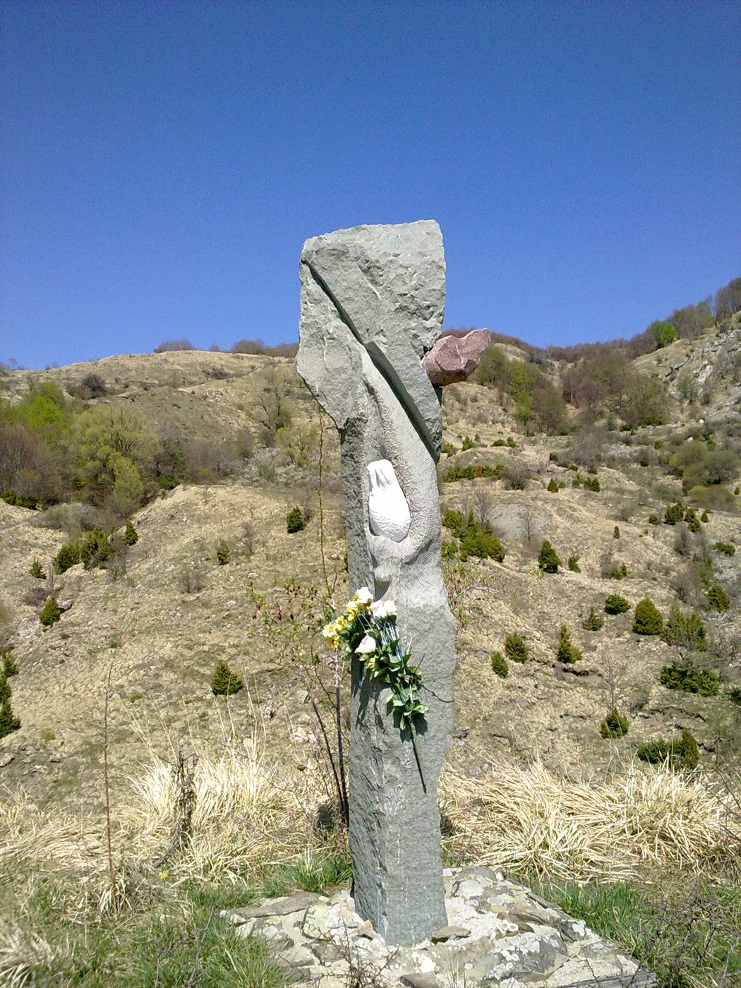 Monumento commemorativo a Fiorini, Giovannini e Donadelli, con un paesaggio naturale sullo sfondo.