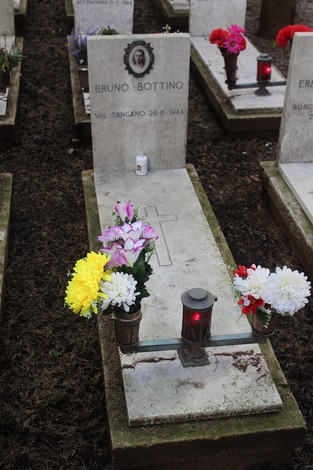 Tombe con fiori e candele dedicate ai caduti per la Libertà, in un cimitero commemorativo.