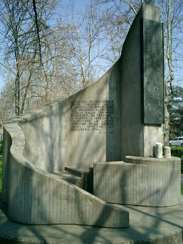Monumento alla Resistenza, struttura in cemento con forme sinuose e iscrizioni commemorative, circondato da alberi.