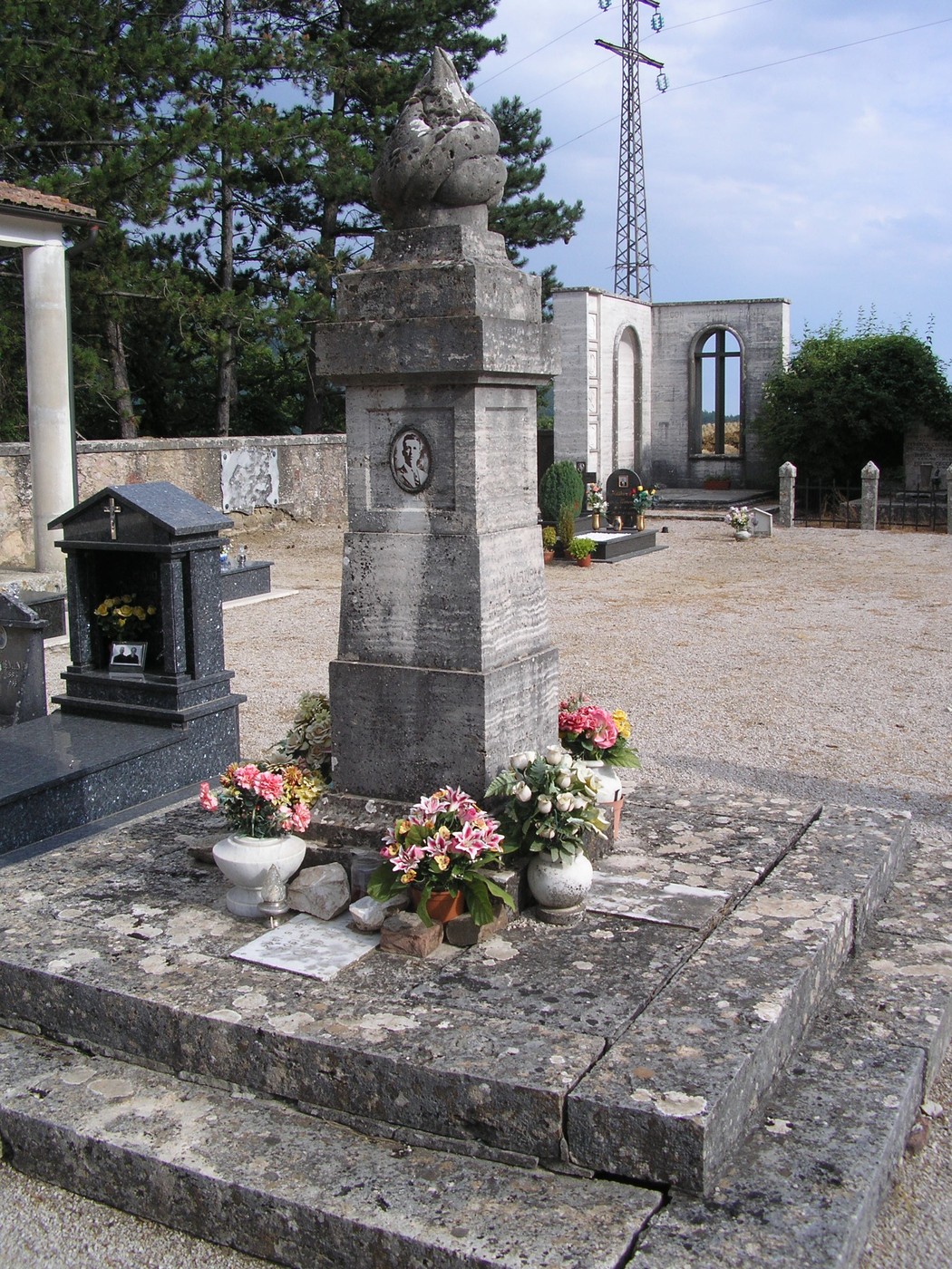 Monumento commemorativo ai partigiani, circondato da fiori e pietre, in un contesto di quiete e memoria.