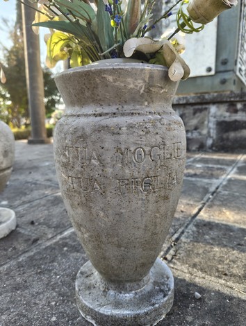 Vaso decorativo in pietra con fiori, collocato in un contesto commemorativo.