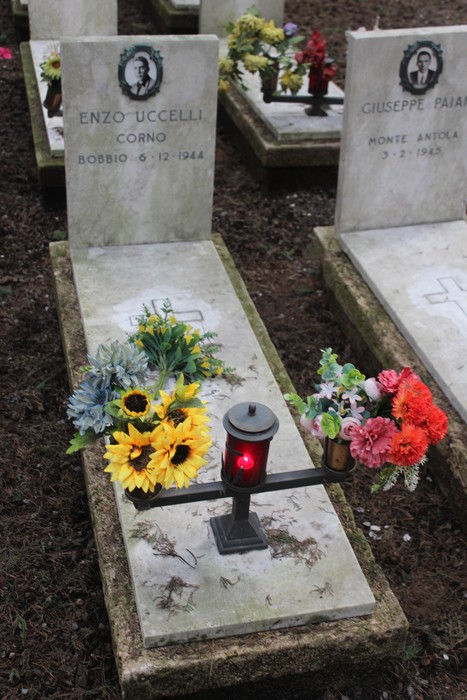 Tombe perpetue dei caduti per la Libertà, decorate con fiori colorati e lume acceso.