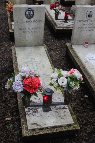 Tombe con fiori e candele in omaggio ai caduti per la Libertà, in un cimitero decorato con rispetto.
