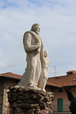 Monumento alla Resistenza con figure di un uomo e una donna su una base di pietra, in un contesto urbano.