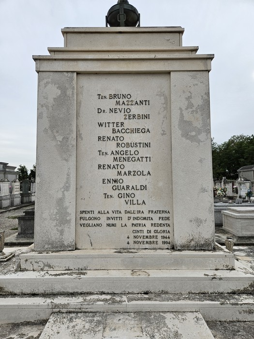 Monumento ai Caduti della Resistenza, con iscrizioni commemorative su una stele in un cimitero.