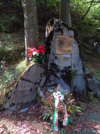 Monumento dedicato alle vittime, con una pietra su cui è apposto un pannello e decorazioni floreali.