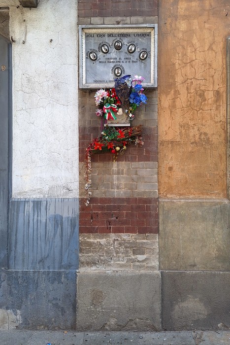 Lapide commemorativa dedicata ai partigiani di Borgo Vittoria con fiori e decorazioni.
