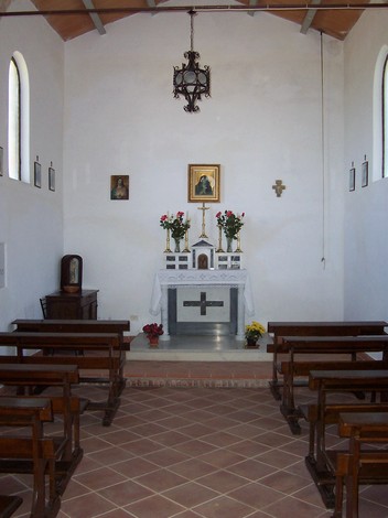 Interno della Cappella dei caduti di Monte Bottigli, con altare e panchine in un ambiente semplice e sobrio.