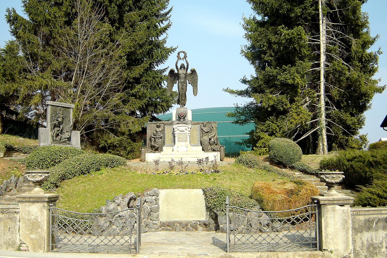 Monumento ai caduti di Sordevolo, un omaggio ai soldati, circondato da verde e simboli di ricordo.