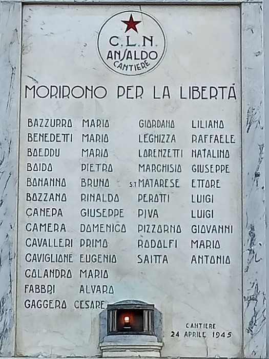 Lapide in marmo con stella rossa e simbolo C.L.N. Ansaldo, elenco di nomi e lumino votivo alla base.