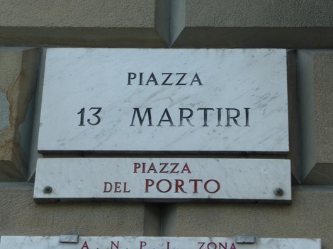 Targa che indica "Piazza 13 Martiri" e "Piazza del Porto" su fondo marmoreo.