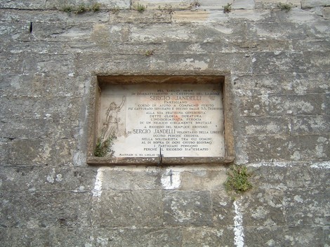 Lapide commemorativa dedicata a Serciò Jandelli, situata su una parete in pietra.