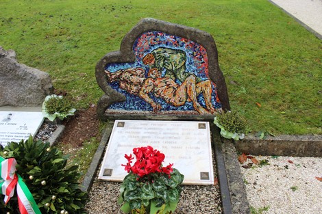 Monumento ai caduti partigiani russi, con mosaico e dedica commemorativa in un contesto verde curato.