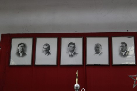 Monumento ai caduti dell'Ansaldo Elettrotecnico con ritratti in bianco e nero su sfondo rosso.