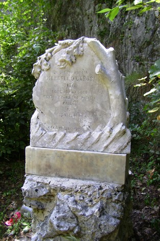 Cippo commemorativo dedicato a Marcello Garosi, situato in una zona naturale.