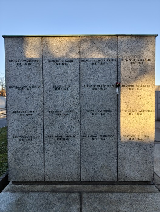 Monumento commemorativo con nomi incisi, dedicato a caduti, immerso in un'atmosfera serena.
