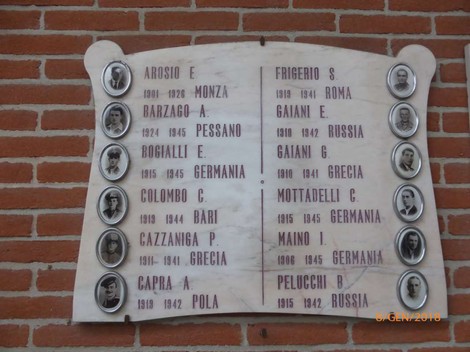 Lapide commemorativa con nomi di caduti di Barzago, decorata con foto e date storiche di guerra.