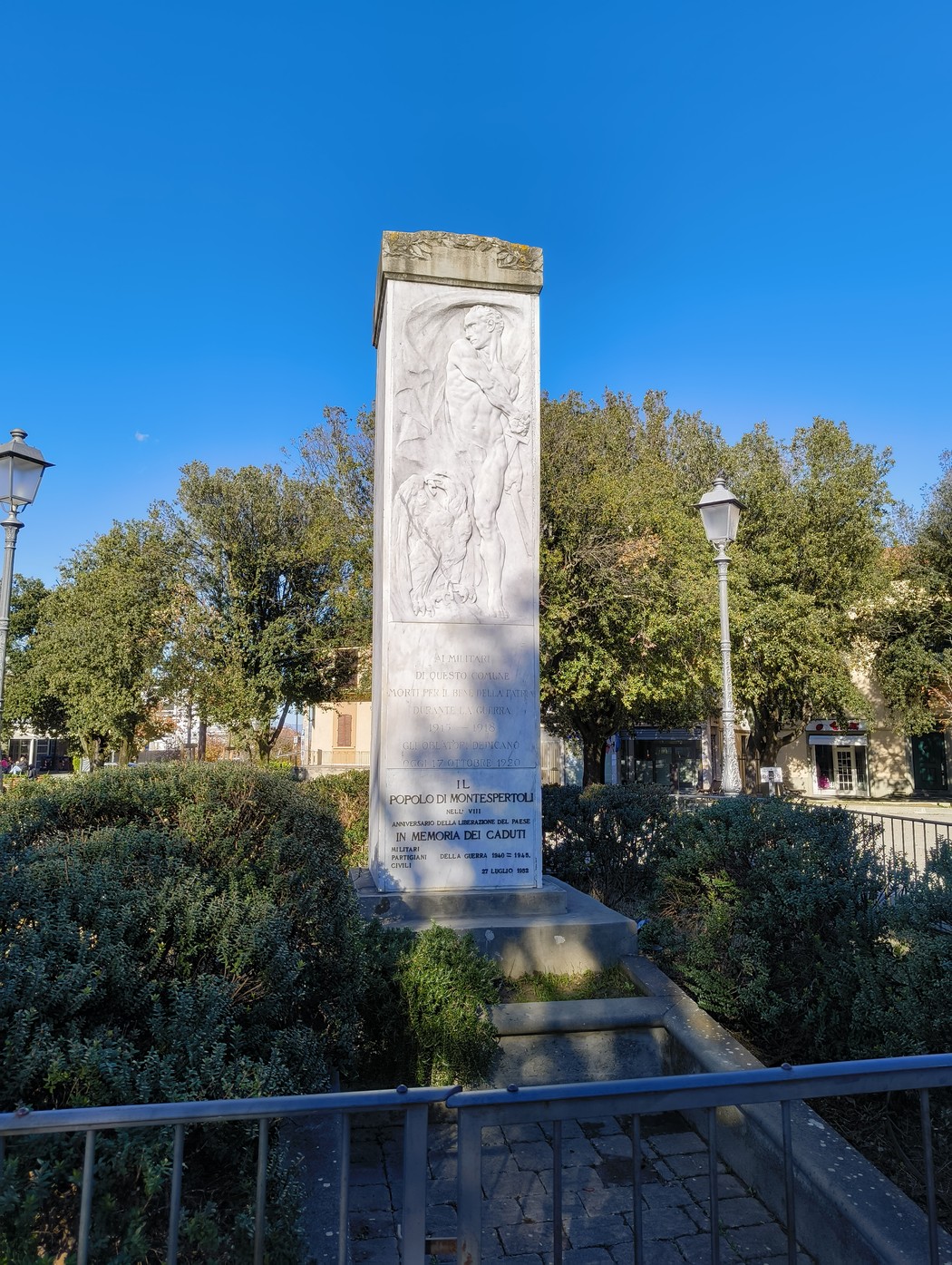 Monumento ai caduti di Montespertoli, dedicato alla memoria dei soldati, immerso nel verde e sotto un cielo blu.