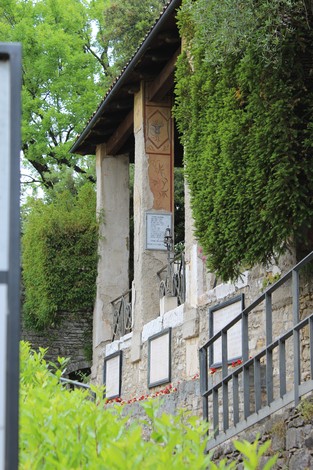 Lapide commemorativa in un ambiente verde, dedicata ai perseguitati politici, con dettagli architettonici storici.