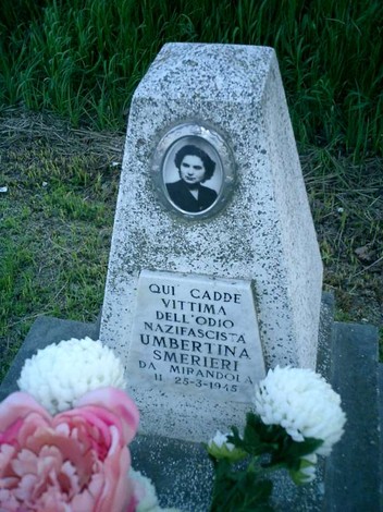 Cippo commemorativo dedicato a Umbertina Smerieri, vittima del nazifascismo a Mirandola, con fiori.