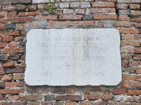 Lapide commemorativa dedicata ai Cremonesi caduti nella guerra di Liberazione, affissa su un muro di mattoni.