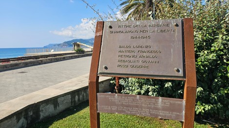 Targa commemorativa dedicata ai caduti per la libertà, affacciata su un lungomare panoramico.