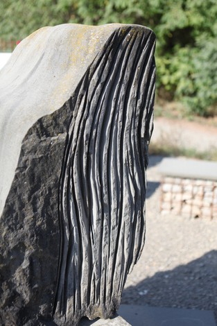 Dettaglio di un monumento in pietra con superfici incise, protagonista di un memoriale commemorativo.