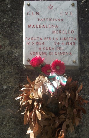 Lapide commemorativa di Maddalena Merello, partigiana, con fiori e un festone di foglie.