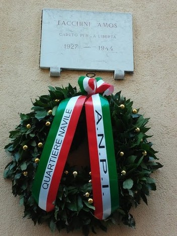 Lapide commemorativa dedicata a Facchini Amos, caduto per la libertà, adornata da una corona di alloro.