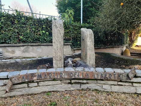 Monumento ai Martiri della Libertà, con stele in pietra e giardino circostante, simbolo di commemorazione.