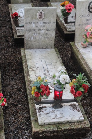 Tombe di caduti per la Libertà, con fiori e lumini commemorativi su lastre in marmo.