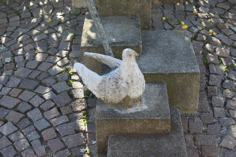 Monumento alla Resistenza con sculture e elementi paesaggistici in un contesto urbano di ciottoli.