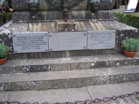 Monumento ai caduti, dedicato ai partigiani, con iscrizioni commemorative e decorazioni floreali.