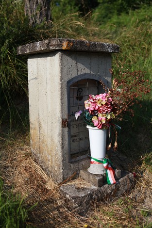 Cippo a Venturi con fiori freschi e decorazioni. Ambiente naturale circostante.