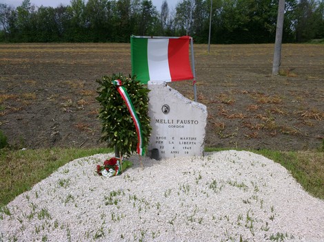 Cippo commemorativo dedicato a Fausto Melli, martire per la libertà, con tricolore italiano e decorazioni floreali.