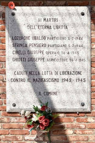 Monumento commemorativo in onore dei martiri della libertà, con una rosa e una dedica scolpita.