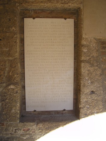 Lapide commemorativa sul muro del municipio, con iscrizioni storiche significative.