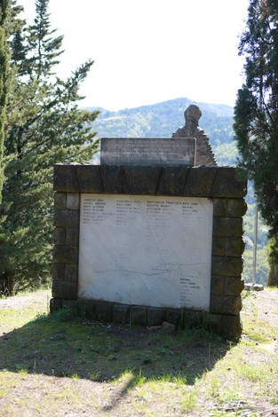 Monumento ai caduti di Purocielo, con base in pietra e iscrizioni commemorative, immerso nella natura circostante.