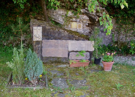 Area monumentale ai Caduti di Partina, con stele commemorativa e decorazioni floreali in un contesto naturale.