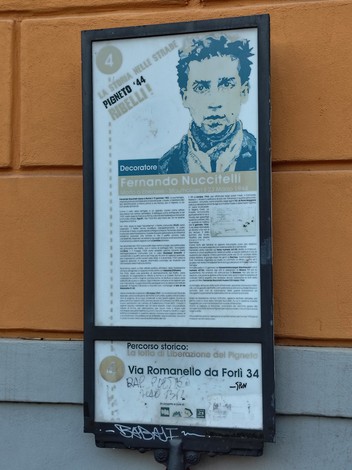 Lapide che commemora il decoratore Fernando Nuccitelli, situata in un contesto urbano del Pigneto.