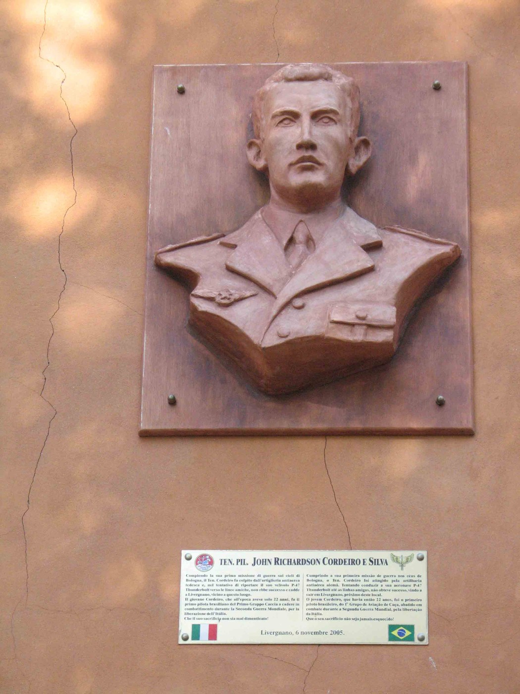 Busto commemorativo di John Richardson Cordeiro e Silva, in rilievo su una parete con targa informativa.