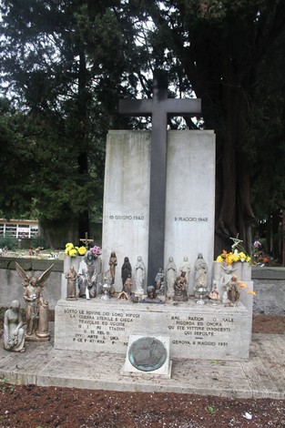 Monumento commemorativo alle vittime civili, con una grande croce e statue di dedicazione adornate da fiori.