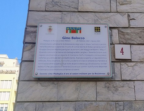 Targa in marmo con iscrizione dedicata a Gino Balocco, affissa su parete in pietra di un edificio.