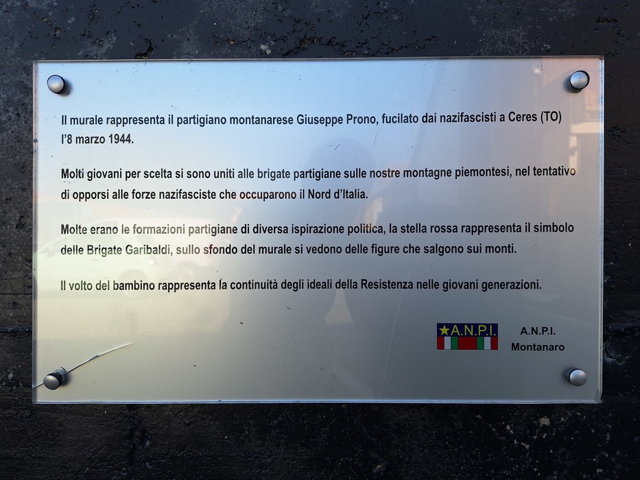 Targa commemorativa in plexiglass fissata a una parete, con testo esplicativo e logo ANPI.