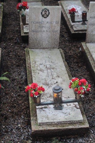 Tombe commemorative con fiori e luci in memoria dei caduti per la Libertà. Atmosfera di rispetto e commemorazione.