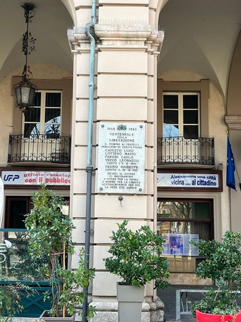 Lapide commemorativa che celebra il ventennale della Liberazione, situata su un pilastro di un edificio storico.