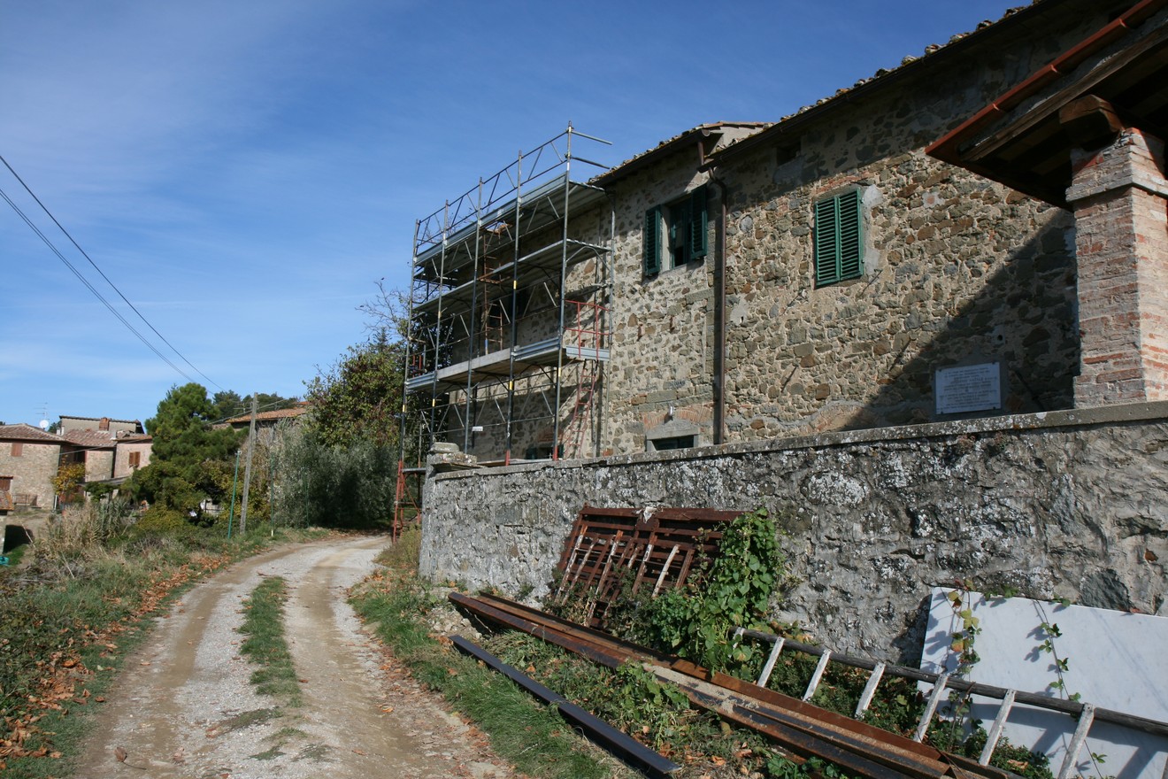 Lapide ad Ardinghi, edificio in pietra con impalcature su una strada di campagna, natura circostante.